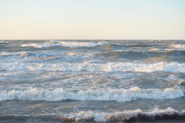 Gün batımında Baltık kıyısı. Yumuşak altın güneş ışığı, parlayan gökyüzü, dalgalar. Idyllic deniz manzarası. Seyahat yerleri, eko turizm, doğa, hava durumu, iklim değişikliği. Resimli panoramik manzara