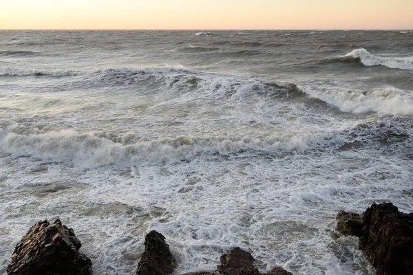 Gün batımında Baltık kıyısı. Yumuşak altın güneş ışığı, parlayan gökyüzü, dalgalar. Idyllic deniz manzarası. Seyahat yerleri, eko turizm, doğa, hava durumu, iklim değişikliği. Resimli panoramik manzara