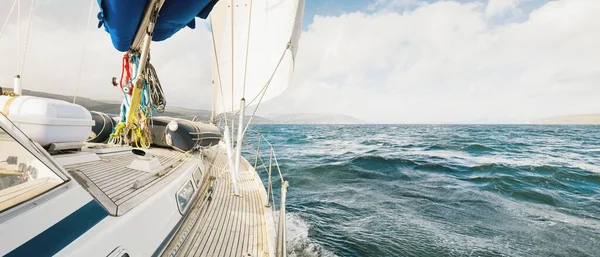 Teknelerle donatılmış modern bir yat. Tahta meşe güverteli. Clyde Nehri Firth 'ün kayalık kıyılarına doğru yol alıyorlar. Dramatik bir gökyüzü. İskoçya, İngiltere. Seyahat yerleri, eko turizm, tatiller, saf doğa.