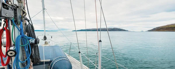 Bulutlu bir günde, Jura adasının kayalık kıyılarında seyir halindeki ahşap meşe güvertesiyle donatılmış modern bir yat. Inner Hebrides, İskoçya, İngiltere. Spor, eğlence, gezi, seyahat yerleri.