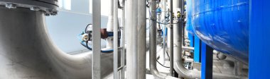 Büyük endüstriyel su arıtma ve kazan dairesi. Parlak çelik borular, mavi pompalar ve vanalar. Sanayi, teknoloji, kimya, ısıtma, iş güvenliği, teçhizat, arz, altyapı