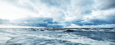 Kışın Baltık Denizi 'nin üzerindeki fırtına bulutları, uzun pozlama. Dramatik günbatımı gökyüzü, dalgalar ve su sıçramaları. Koyu deniz manzarası. Almanya