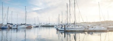 Yelkenliler gün batımında bir rıhtıma demirlediler. Yakından. Cascais, Portekiz 'de yat marinası. Suyun simetri yansımaları. Yelkencilik, spor, eğlence, eğlence, tatil, seyahat yerleri.