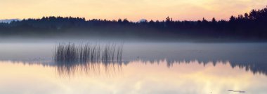 Yaz gündönümü gecesinde Saimaa Gölü 'nün üzerinde gece parlayan bulutlar ve sis vardı. Altın güneş ışığı. Uzun pozlama. Destansı bulut manzarası. Doğal desen. Suyun simetri yansımaları. Finlandiya