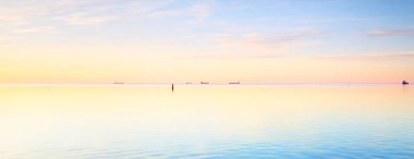 Gün batımında donmuş Saima gölünün karla kaplı kıyılarının panoramik görüntüsü. Göz kamaştırıcı pembe bulutlar. Suyun simetri yansımaları. Kış Harikalar Diyarı. Finlandiya