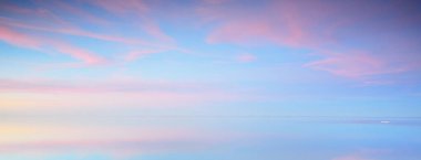 Gün batımında donmuş gölün panoramik manzarası. Göz kamaştırıcı pembe bulutlar. Suyun simetri yansımaları. Kış harikalar diyarı, saf doğa. Finlandiya