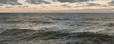 Gün batımında açık Baltık denizinin panoramik görüntüsü. Su yüzeyi dokusu, dalgalar. Dengesiz hava, kış, iklim değişikliği, okyanus kabarması, doğa.