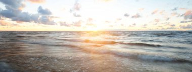 Gök gürültülü fırtınadan sonra denizin üstünde destansı, parlak, altın renkli günbatımı bulutları. Dramatik bir gökyüzü. Dalgalar ve su dokuya sıçrar. Idyllic deniz manzarası. Kavramsal görüntü, uzun pozlama. Resim gibi bir manzara.