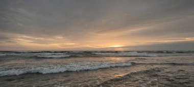 Gün batımında Anholt Adası 'nın kumsal kıyısında. Dalgalar ve su sıçramaları. Renkli bulutlu bir manzara. Çevre koruma, eko-turizm, gezi teması. Kattegat, Danimarka