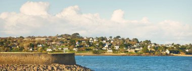 Douarnenez körfezinin kumlu sahilindeki kır evleri ve ağaçlar. Açık mavi gökyüzü. Gök mavisi suyu. Brittany, Fransa. Seyahat yerleri, geziler, tatil teması