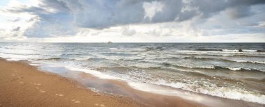 Gün batımında fırtınadan sonra Baltık Denizi 'nin üzerinde kümülüs bulutları olan mavi gökyüzü. İnsan izleri ve kum dokusu, yakın plan. Idyllic manzara. Ilık güneş ışığı. Seyahat yerleri, eko turizm