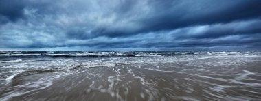 Kışın karanlık fırtına bulutlarının altında kuzey denizi, uzun süre açık. Dalgalar ve su sıçramaları. Koyu deniz manzarası. Hollanda 'da. Panoramik görünüm