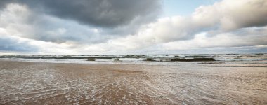 Gün batımından önce Baltık Denizi 'nin üzerinde parlayan kümülüs bulutlarıyla dramatik mavi gökyüzü. Kumlu bir sahilden görüntü. Avrupa 'da sonbahar, kışın başı. Idyllic deniz manzarası. Kararsız hava, iklim değişikliği, ekoloji