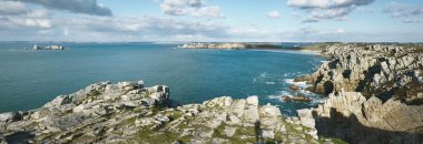 Pointe de Pen-Hir 'in kayalık sahili, uçurumlara yakın. Bulutlu mavi gökyüzü, masmavi su, fırtınalı dalgalar. Dramatik bulut manzarası. Crozon Yarımadası, Britanya, Fransa
