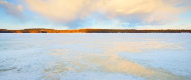Gün batımında donmuş göl ve karla kaplı çam ormanı. Buz dokusu. Dramatik gökyüzü, yumuşak güneş ışığı. Idyllic kış sahnesi. Doğa, çevre koruma, ekoloji, iklim değişikliği, eko-turizm, Noel