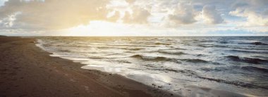 Gün batımında fırtınadan sonra Baltık Denizi kıyısında parlayan kümülüs bulutlarıyla açık bir gökyüzü. Dramatik bulut manzarası. Yumuşak altın güneş ışığı. Resimli bir manzara var. Kararsız hava, doğa, iklim değişikliği