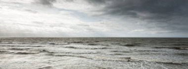 Gün batımında Baltık kıyıları (kum tepeleri). Yumuşak güneş ışığı, dramatik gökyüzü, dalgalar ve su sıçramaları. Idyllic deniz manzarası. Letonya, Avrupa. Bahar, hava, iklim değişikliği, doğa. Panorama, boşluğu kopyala