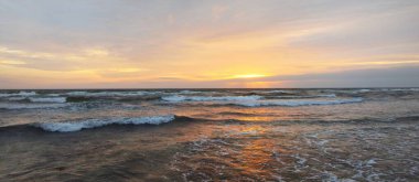 Gün batımında Anholt Adası 'nın kumsal kıyısında. Dalgalar ve su sıçramaları. Renkli bulutlu bir manzara. Çevre koruma, eko turizm teması. Kattegat, Danimarka