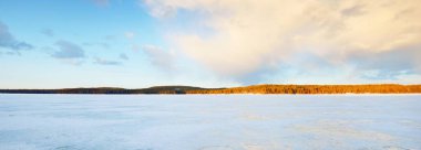 Gün batımında donmuş göl ve karla kaplı çam ormanı. Buz dokusu. Dramatik gökyüzü, yumuşak güneş ışığı. Idyllic kış sahnesi. Doğa, çevre koruma, ekoloji, iklim değişikliği, eko-turizm, Noel