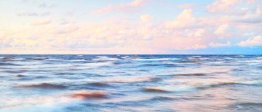 Gök gürültülü bir fırtınadan sonra denizin üstünde destansı pembe gün batımı bulutları. Dramatik bir gökyüzü. Dalgalar ve su dokuya sıçrar. Idyllic deniz manzarası. Kavramsal görüntü, uzun pozlama. Resim gibi bir manzara.