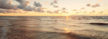 Gök gürültülü fırtınadan sonra denizin üstünde destansı, parlak, altın renkli günbatımı bulutları. Dramatik bir gökyüzü. Dalgalar ve su dokuya sıçrar. Idyllic deniz manzarası. Kavramsal görüntü, uzun pozlama. Resim gibi bir manzara.