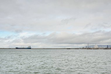 Fırtınadan sonra Baltık Denizi. Kargo iskele terminali. Dramatik bir gökyüzü. Parlayan bulutlar. Doğa, çevre, endüstri, nakliye, lojistik, küresel iletişim, ekonomi