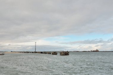 Fırtınadan sonra Baltık Denizi. Kargo iskele terminali. Dramatik bir gökyüzü. Parlayan bulutlar. Doğa, çevre, endüstri, nakliye, lojistik, küresel iletişim, ekonomi