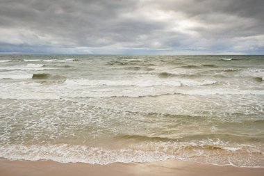 Baltic sea during the storm. Dramatic sky, dark glowing clouds. Waves, water splashes. Idyllic seascape. Climate change, nature, fickle weather, ecology
