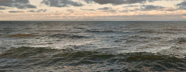 Gün batımında açık Baltık denizinin panoramik görüntüsü. Su yüzeyi dokusu, dalgalar. Dengesiz hava, kış, iklim değişikliği, okyanus kabarması, doğa.