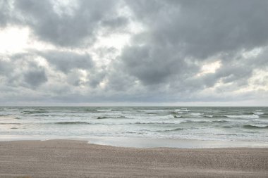 Baltık kıyıları (kum tepeleri) fırtınadan sonra gün batımında. Dramatik gökyüzü, parlayan bulutlar, rüzgar. Sonbahar manzarası. Doğa, çevre, ekoloji, kararsız hava, iklim değişikliği