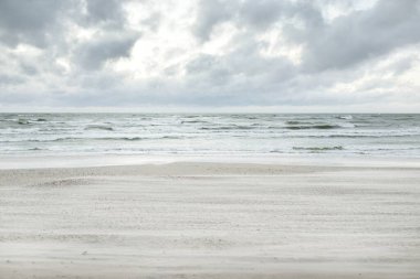 Baltık kıyıları (kum tepeleri) fırtınadan sonra gün batımında. Dramatik gökyüzü, parlayan bulutlar, rüzgar. Sonbahar manzarası. Doğa, çevre, ekoloji, kararsız hava, iklim değişikliği