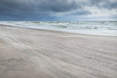 Baltık kıyıları (kum tepeleri) fırtınadan sonra gün batımında. Dramatik gökyüzü, parlayan bulutlar, rüzgar. Sonbahar manzarası. Doğa, çevre, ekoloji, kararsız hava, iklim değişikliği