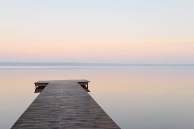 Forest lake (river) at sunrise. Wooden pier (boardwalk). Soft sunlight, mist, reflections on water. Idyllic autumn landscape. Pure nature, ecotourism, hiking, exploring