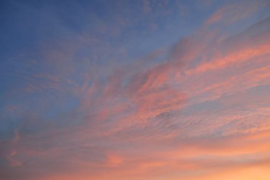 Açık mavi gökyüzü. Pembe ve altın renkli bulutlar. Gün doğumu. Dramatik bulut manzarası. Sanat, meteoroloji, cennet, umut, barış, grafik kaynakları, resimli panoramik manzara