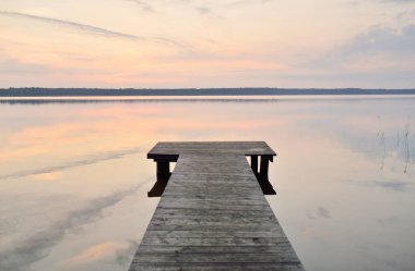 Forest lake (river) at sunrise. Wooden pier (boardwalk). Soft sunlight, mist, reflections on water. Idyllic autumn landscape. Pure nature, ecotourism, hiking, exploring
