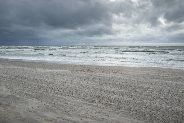 Baltık kıyıları (kum tepeleri) fırtınadan sonra gün batımında. Dramatik gökyüzü, parlayan bulutlar, rüzgar. Sonbahar manzarası. Doğa, çevre, ekoloji, kararsız hava, iklim değişikliği