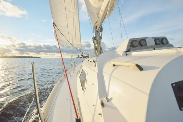 Gün batımında açık denizde yelken açmak. Güvertenin yakın görüntüsü, direk ve yelkenler. Yağmurdan sonra açık gökyüzü, çarpıcı parlayan bulutlar, altın güneş ışığı, dalgalar ve su sıçramaları, kasırga. Destansı deniz manzarası