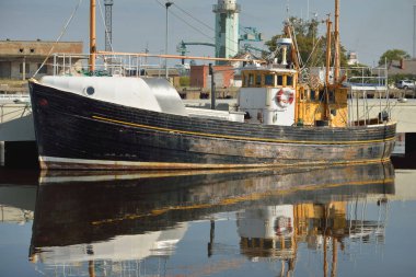 An old wooden classic North sea fishing boat moored to a pier in a yacht marina. Nautical vessel, transportation, traditional craft, industry