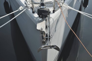 Beyaz modern yelkenli (kiralık ve satılık) yat limanındaki bir rıhtıma demirlemiş. Tahta meşe güvertesi. Denizcilik, ulaşım, amatör yelkencilik, tatiller, gezinti, eğlence kavramları