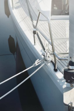 White modern sailboat (for rent and sale) moored to a pier in a yacht marina. Wooden teak deck. Nautical vessel, transportation, amateur sailing, vacations, cruising, recreation concepts