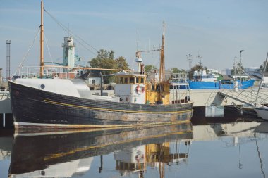 Eski bir ahşap klasik Kuzey Denizi balıkçı teknesi yat limanındaki bir rıhtıma demirlemiş. Denizcilik gemisi, ulaşım, geleneksel zanaat, sanayi
