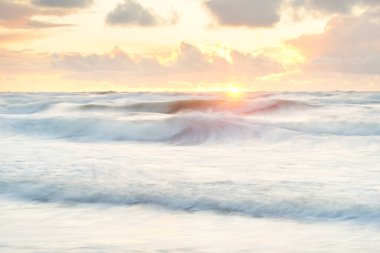 Deniz dalgaları ve sıçrama dokusu. Renkli gökyüzü suya yansıyor. Idyllic deniz manzarası. Kavramsal görüntü, uzun pozlama. Resimli bir manzara var. Arkaplan, duvar kağıdı, doğal desen, grafik kaynakları