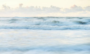 Deniz dalgaları ve sıçrama dokusu. Renkli gökyüzü suya yansıyor. Idyllic deniz manzarası. Kavramsal görüntü, uzun pozlama. Resimli bir manzara var. Arkaplan, duvar kağıdı, doğal desen, grafik kaynakları