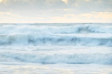 Deniz dalgaları ve sıçrama dokusu. Renkli gökyüzü suya yansıyor. Idyllic deniz manzarası. Kavramsal görüntü, uzun pozlama. Resimli bir manzara var. Arkaplan, duvar kağıdı, doğal desen, grafik kaynakları