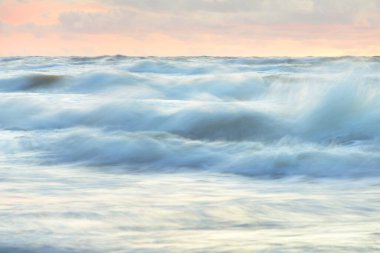 Deniz dalgaları ve sıçrama dokusu. Renkli gökyüzü suya yansıyor. Idyllic deniz manzarası. Kavramsal görüntü, uzun pozlama. Resimli bir manzara var. Arkaplan, duvar kağıdı, doğal desen, grafik kaynakları