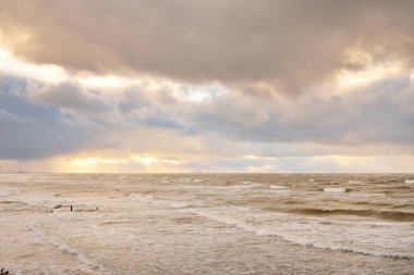 Baltic sea at sunset. Dramatic sky, blue and pink glowing clouds, golden sunlight. Waves, splashing water. Picturesque scenery, seascape, nature. Panoramic view, long exposure