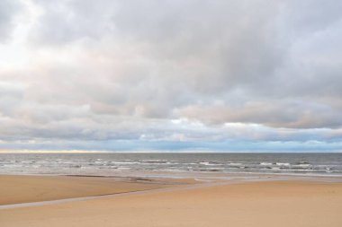 Gün batımında Baltık kıyısı. Kumsal manzarası (kum tepeleri). Dramatik günbatımı gökyüzü, parlayan bulutlar. Idyllic manzara. Doğa, tatiller, eğlence. Çevre turizmi. Panoramik görünüm