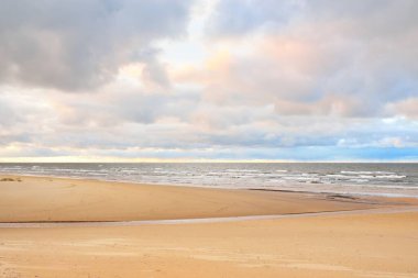 Gün batımında Baltık kıyısı. Kumsal manzarası (kum tepeleri). Dramatik günbatımı gökyüzü, parlayan bulutlar. Idyllic manzara. Doğa, tatiller, eğlence. Çevre turizmi. Panoramik görünüm