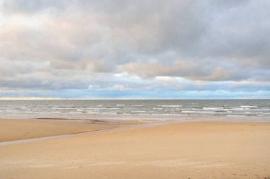 Gün batımında Baltık kıyısı. Kumsal manzarası (kum tepeleri). Dramatik günbatımı gökyüzü, parlayan bulutlar. Idyllic manzara. Doğa, tatiller, eğlence. Çevre turizmi. Panoramik görünüm