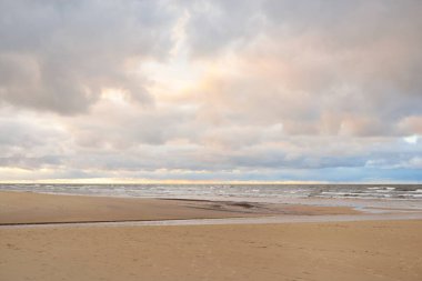 Gün batımında Baltık kıyısı. Kumsal manzarası (kum tepeleri). Dramatik günbatımı gökyüzü, parlayan bulutlar. Idyllic manzara. Doğa, tatiller, eğlence. Çevre turizmi. Panoramik görünüm